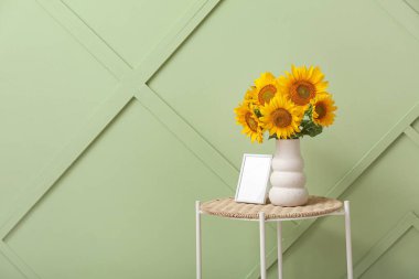 Güzel ayçiçekli vazo ve boş çerçeve yeşil duvarın yanındaki odada.