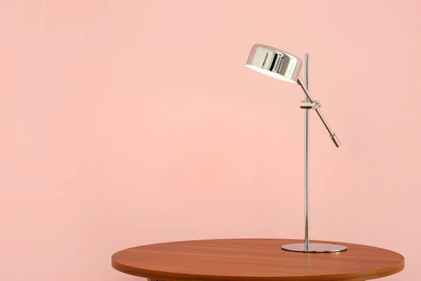 粉红墙壁附近木制桌子上明亮的台灯 — 图库照片