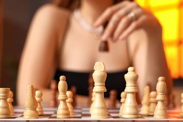 Woman and chess pieces on game board, closeup