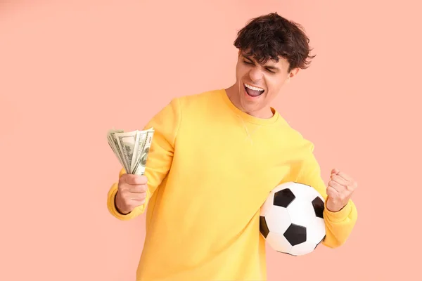 サッカーボールとピンクのバックグラウンドでお金を持つ幸せな若者 スポーツベットコンセプト — ストック写真