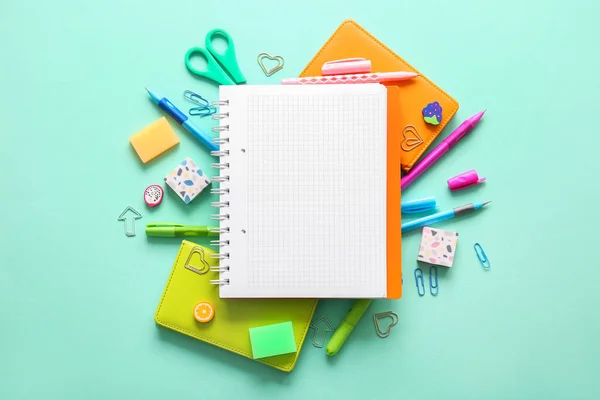 蓝绿色背景的空白笔记本和不同学校文具的作文 — 图库照片