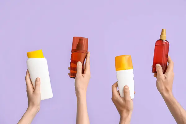 Руки Женщины Бутылками Крема Загара Сиреневом Фоне — стоковое фото