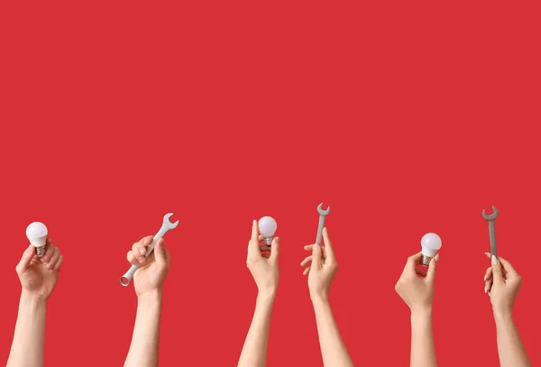 Kırmızı Arka Planda Ampullü Anahtarlı Elektrikçi Elleri — Stok fotoğraf