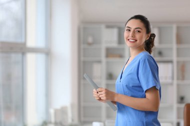 Klinikte panosu olan kadın bir tıp asistanı.