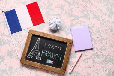 Üzerinde Learn FRENCH, defter, buruşuk kâğıt ve grunge arkaplan üzerine Fransa bayrağı olan yazı tahtası.