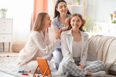 Yatak odasında makyaj yapan genç kadınlar.