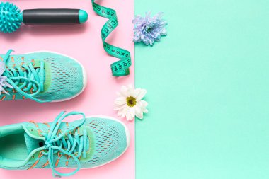Bahar çiçekli spor ayakkabılar, masaj silindiri ve renkli arka planda mezura.