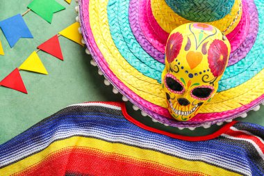 Şapkalı Meksika bayrakları, yeşil arka planda boyalı kafatası ve serape, yakın plan.