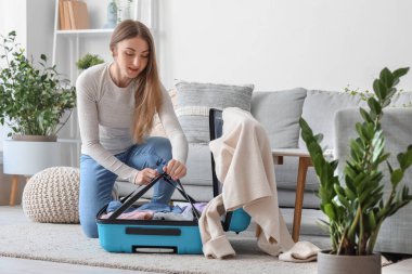 Evde bavulunu boşaltan genç bir kadın.