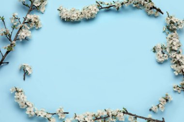 Mavi arkaplanda çiçek açan dallardan oluşan çerçeve