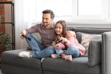 Babası ve küçük kızı evde video oyunu oynuyorlar.