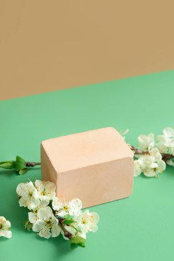 Dekoratif podyum ve çiçek açan dallar yeşil masada.