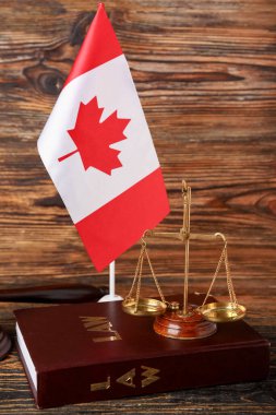Adalet terazisi ve ahşap zemin üzerine hukuk kitabıyla Kanada bayrağı