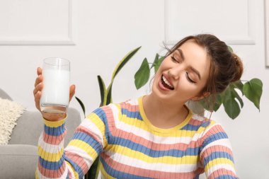 Evde bir bardak sütle genç bir kadın, yakın plan.