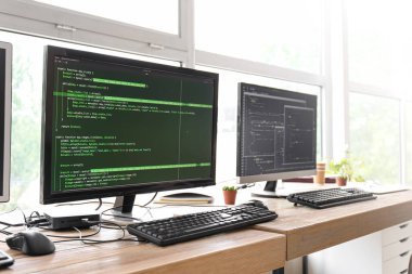 Ofisteki monitörlerde programlama koduna sahip programcının işyeri