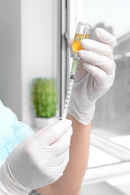 Klinikte şırıngası ve ampülü olan kadın doktor, yakın plan.