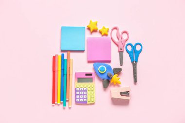 Pembe arka planda farklı kırtasiye malzemeleriyle plastikten yapılmış roket