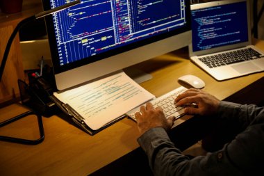 Geceleri ofiste bilgisayarla çalışan erkek programcı, yakın plan.