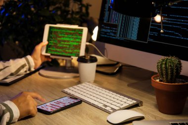 Geceleri cep telefonuyla çalışan kadın programcı, yakın plan.