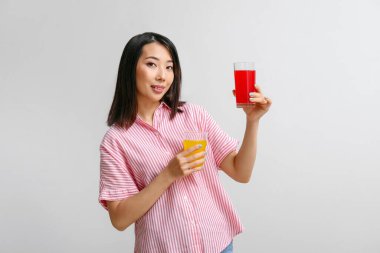 Hafif arka planda meyve suyu bardakları olan güzel Asyalı kadın.