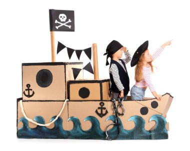 Beyaz arka planda karton gemide oynayan sevimli küçük korsanlar.