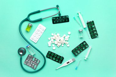 Turkuaz arka planda haplı ve steteskoplu kompozisyon