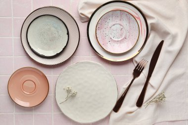 Pembe kaplama masa üzerinde temiz tabaklar ve çatal bıçaklarla kompozisyon