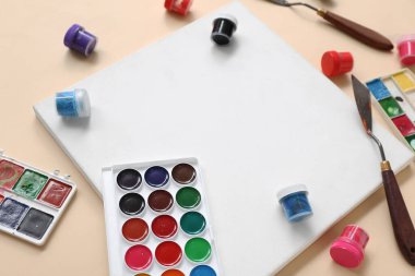 Bej arkaplanda boş tuval ve boyalar, yakın plan