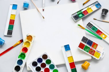 Boş tuval, gri arkaplanda boya ve fırçalar