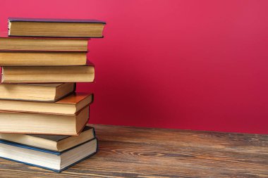 Kırmızı arkaplana karşı ahşap masadaki kitap yığını