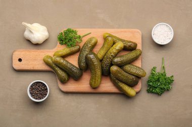 Tahta tahta tahta, salatalık turşusu ve kahverengi arka planda farklı baharatlar.