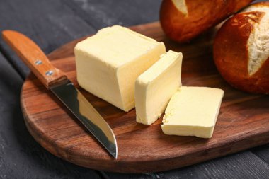 Siyah ahşap zemin üzerinde taze tereyağı ve ekmek olan tahta.