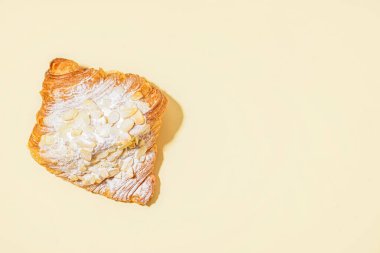 Bej arka planda pudra şekerli ve fındıklı tatlı kruvasan.