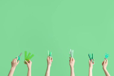 Hands with school accessories on green background
