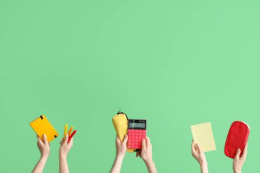 Hands with school accessories on green background