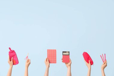 Hands with school supplies on blue background