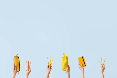 Hands with school supplies on blue background
