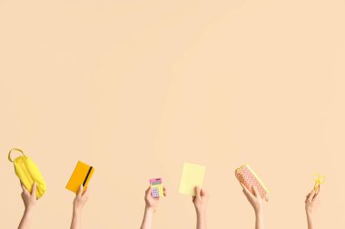 Hands with school supplies on beige background