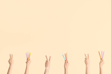 Bej arkaplanda farklı kalemler olan eller