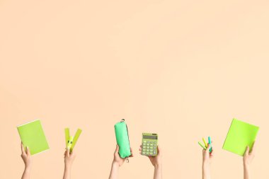 Hands with school supplies on beige background