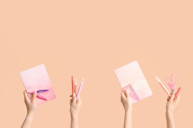 Female hands with school supplies on beige background
