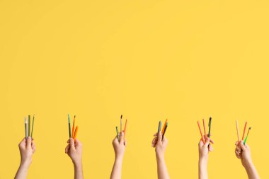 Hands with school supplies on yellow background