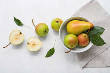 Beyaz masada olgun armutlarla dolu bir kase.