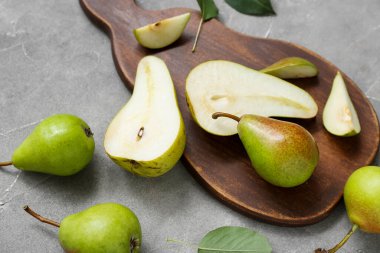 Gri masa üzerinde olgun armutlar olan ahşap tahta, yakın plan.