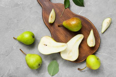 Gri masa üzerinde olgun armutlar olan ahşap tahta, yakın plan.