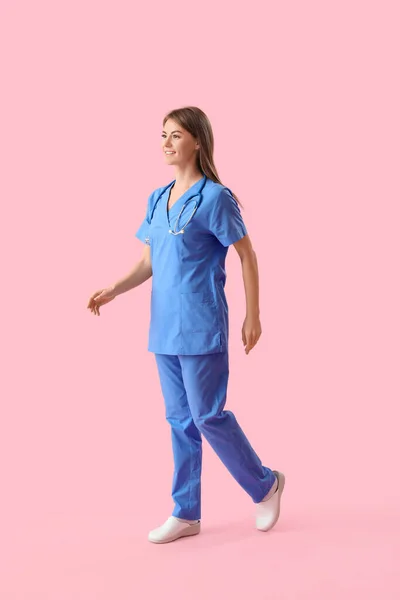 ピンクの背景を歩く女性の医療インターン — ストック写真