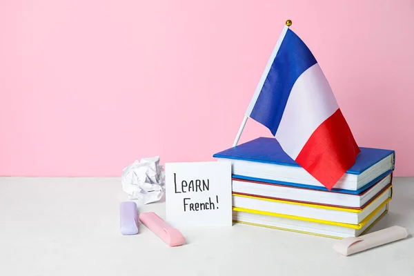テキスト付きの紙ピンクの壁の近くのテーブルの上にフランス語 本を学ぶ — ストック写真
