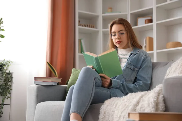 Ung Kvinde Læser Bog Sofaen Derhjemme - Stock-foto