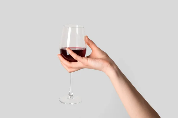 灰色の背景に赤ワインの女性の手を保持ガラス — ストック写真