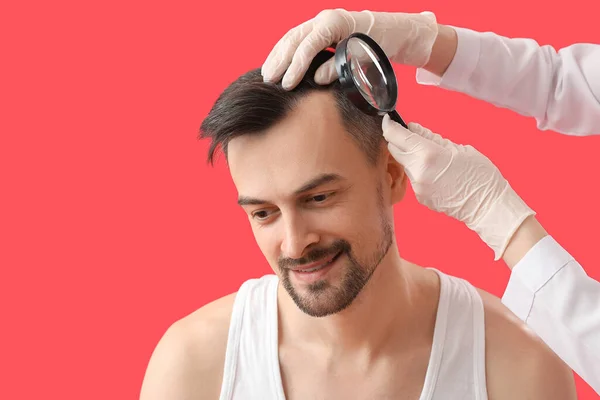 Lékař Zkoumá Vlasy Mladého Muže Lupou Červeném Pozadí Detailní Záběr — Stock fotografie